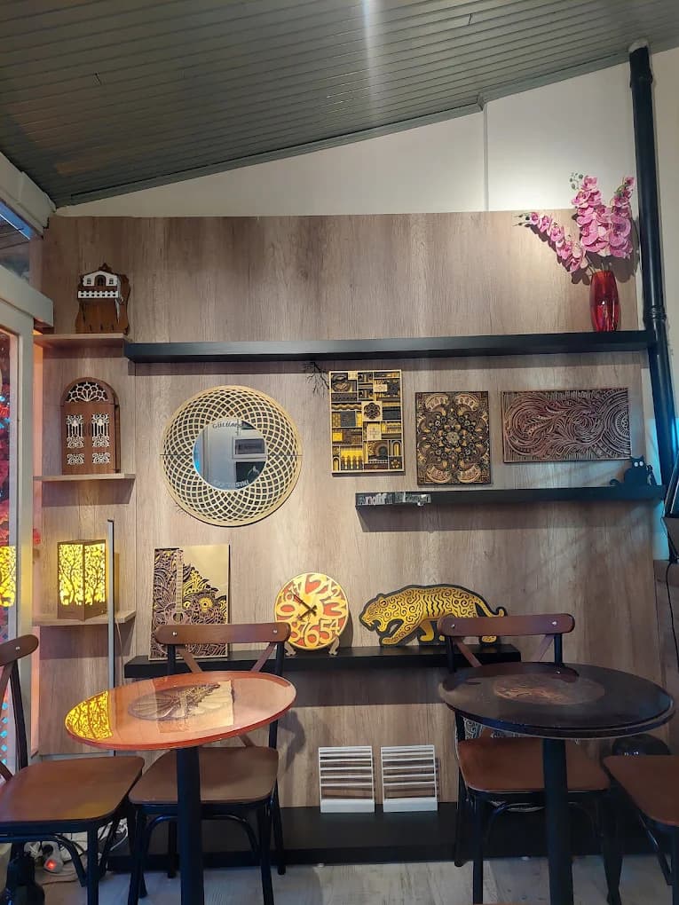 Kafenin ahşap duvarında sergilenen lazer kesim tablolar ve mandala panolar