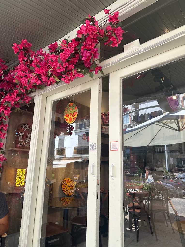 Gündüz ışığında kafenin pembe begonvillerle sarılı camekanı